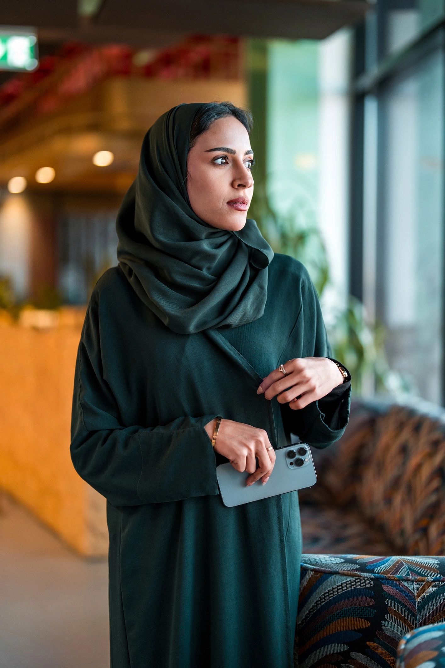 Elegant woman in black abaya by a modern window
